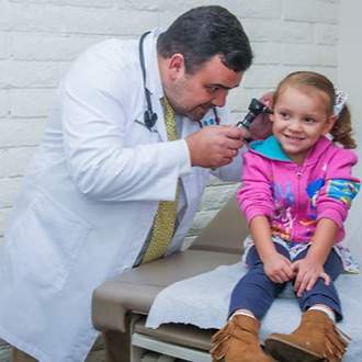about us - a doctor performs a checkup on a little girl