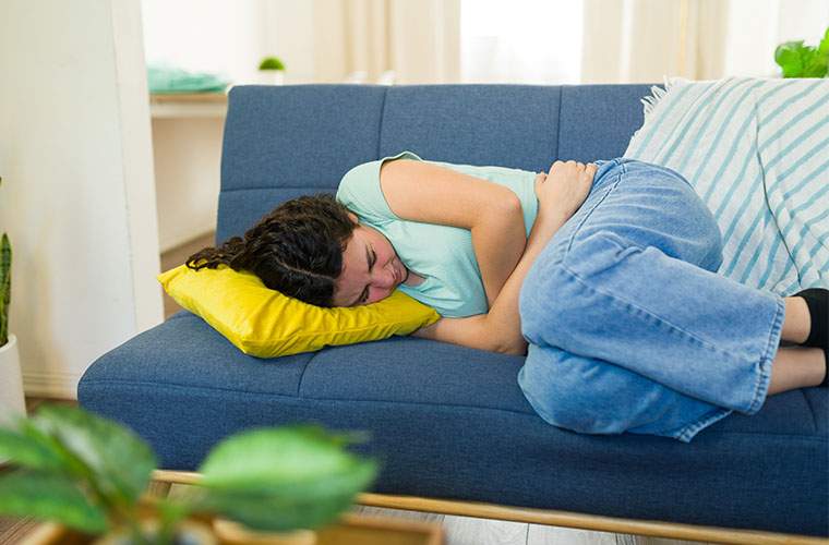 Acute Illness in a woman curled in the fetal position in pain on a sofa