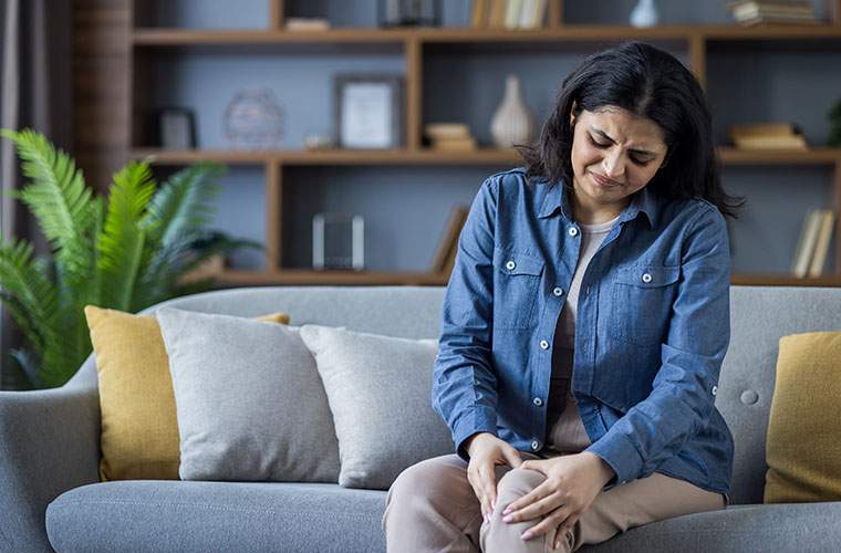 Chronic Illness - a woman clutches her knee in pain