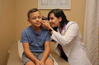 female doctor checks a boys ear during a checkup